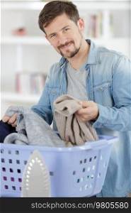portrait of smiling young man holding laundry basket