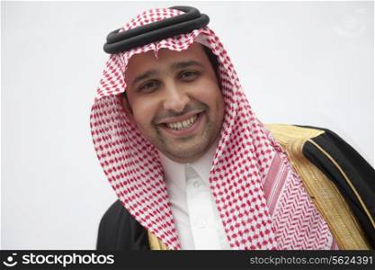 Portrait of smiling young man in traditional Arab clothing and Kaffiyeh, studio shot