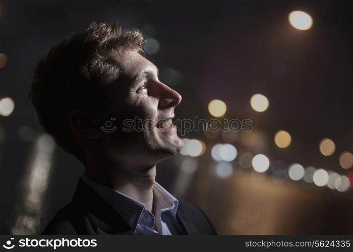Portrait of smiling young man, profile, bright light shining on face, studio shot