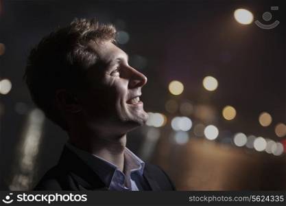 Portrait of smiling young man, profile, bright light shining on face, studio shot