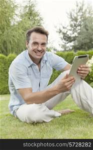 Portrait of smiling young man using tablet computer in park