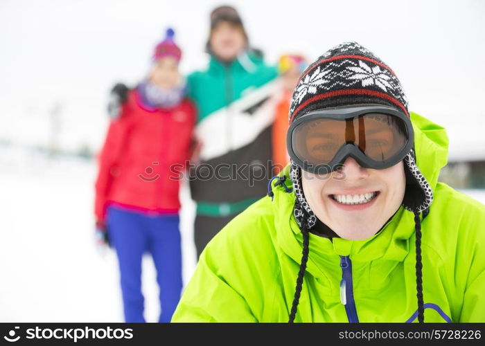 Portrait of smiling young man with friends in background during winter