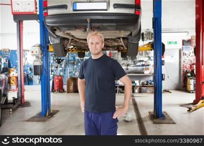 Portrait of smiling young mechanic standing inside his auto repair shop