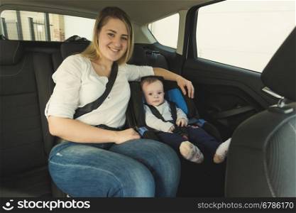 Portrait of smiling young mother and baby boy in car safety seat