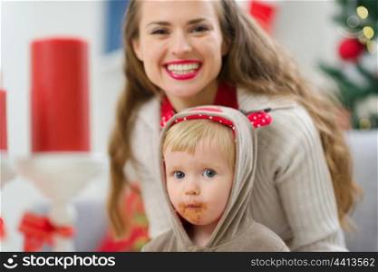 Portrait of smiling young mother and eat smeared baby on Christmas
