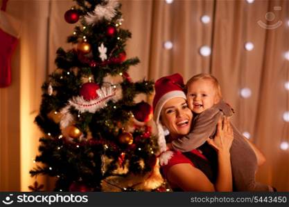 Portrait of smiling young mother with beautiful baby near Christmas tree&#xA;
