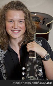 Portrait of smiling young musician with guitar over shoulder