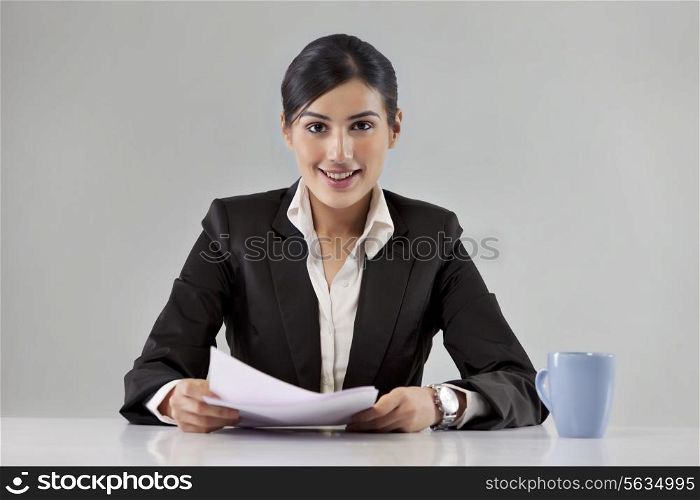 Portrait of smiling young news television host with coffee cup and paper