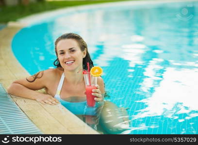 Portrait of smiling young woman at pool with cocktail