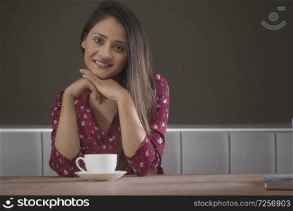 Portrait of smiling young woman at restaurant hand on chin