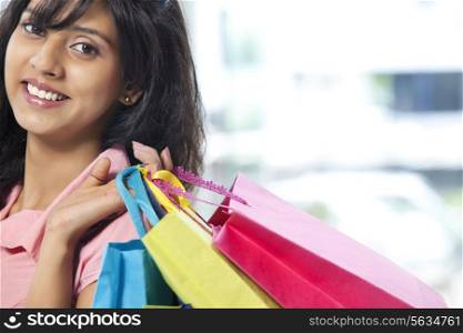 Portrait of smiling young woman carrying shopping bags