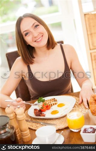 Portrait of smiling young woman having breakfast at home