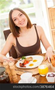 Portrait of smiling young woman having breakfast at home
