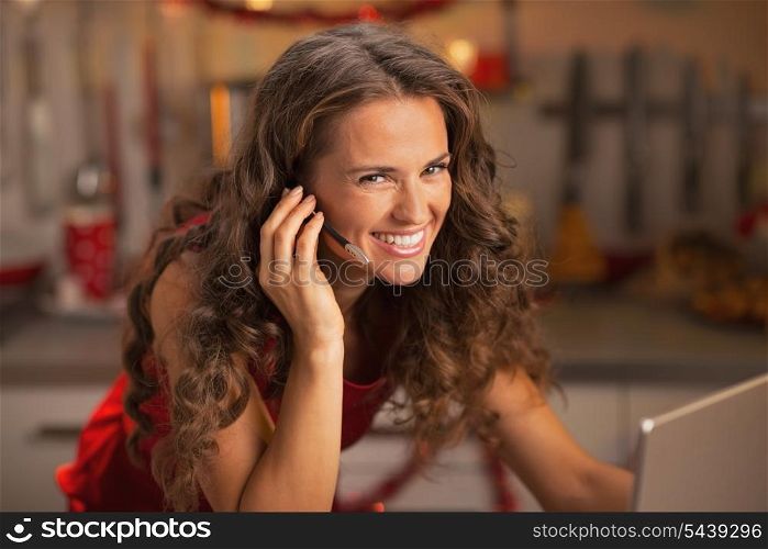 Portrait of smiling young woman having video chat on laptop in christmas decorated kitchen