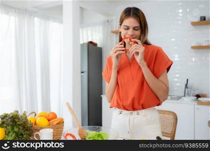 Portrait of smiling young woman holding a red chili in her hands at home