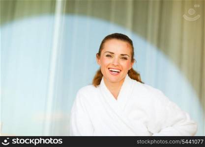 Portrait of smiling young woman in bathrobe sitting on terrace