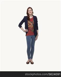 Portrait of smiling young woman in casual clothing, hand on hip, full length, studio shot