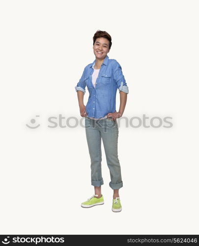 Portrait of smiling young woman in casual clothing, hands on hips, full length, studio shot