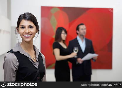 Portrait of smiling young woman in front of a couple in museum