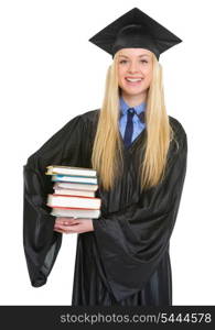 Portrait of smiling young woman in graduation gown holding books