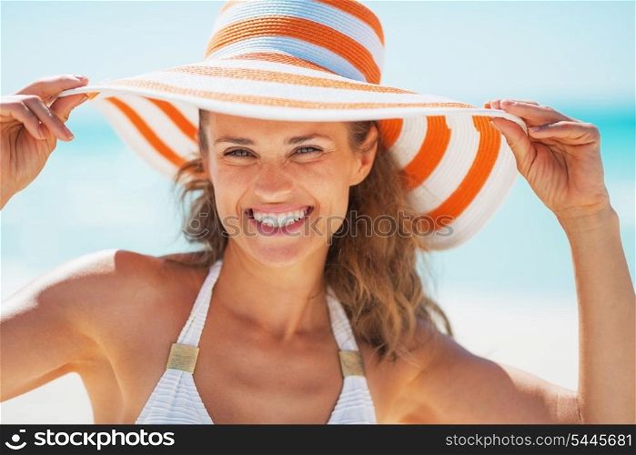 Portrait of smiling young woman in swimsuit and beach hat
