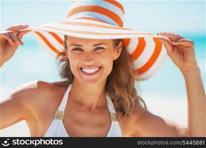 Portrait of smiling young woman in swimsuit and beach hat