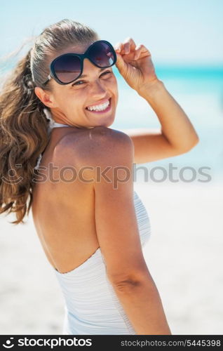 Portrait of smiling young woman in swimsuit with sunglasses on beach