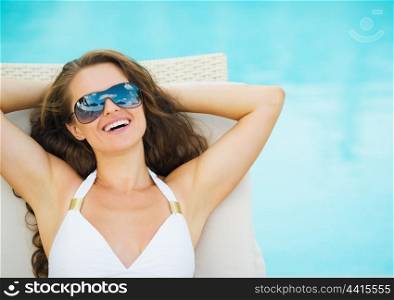 Portrait of smiling young woman laying on sunbed