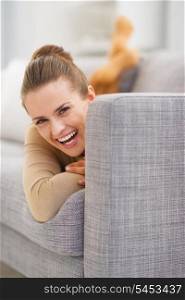 Portrait of smiling young woman looking out from sofa