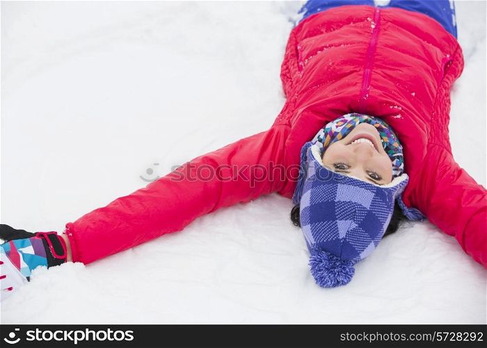Portrait of smiling young woman lying on snow