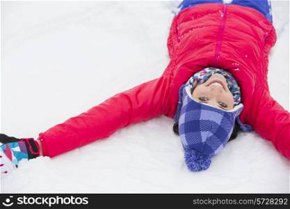 Portrait of smiling young woman lying on snow