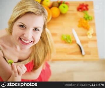 Portrait of smiling young woman making fruits salad
