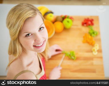 Portrait of smiling young woman making fruits salad