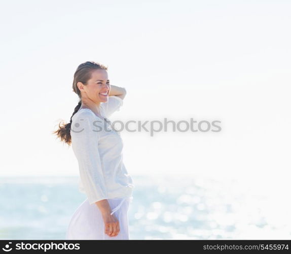 Portrait of smiling young woman on sea shore looking into distance