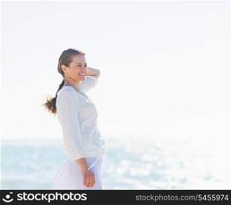 Portrait of smiling young woman on sea shore looking into distance