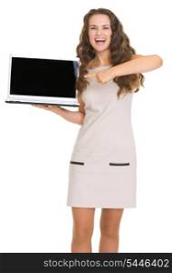 Portrait of smiling young woman pointing on laptop with blank screen