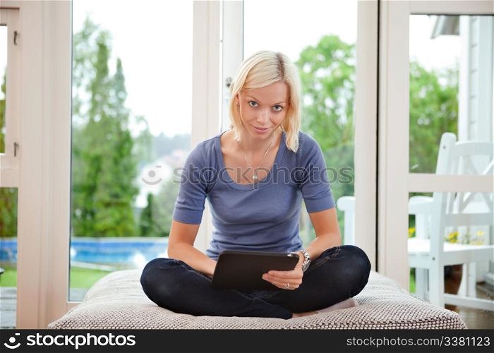 Portrait of smiling young woman sitting on couch and using digital tablet