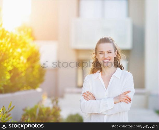 Portrait of smiling young woman standing in front of house building