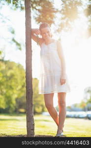 Portrait of smiling young woman standing near seedling tree