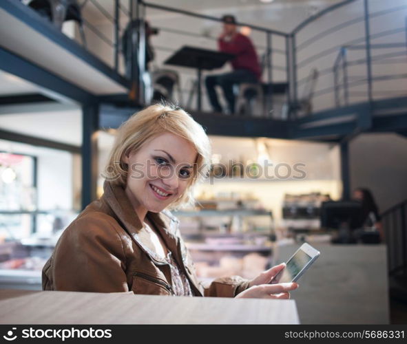 Portrait of smiling young woman using tablet PC in cafe