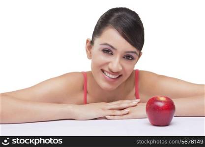 Portrait of smiling young woman with apple over white background