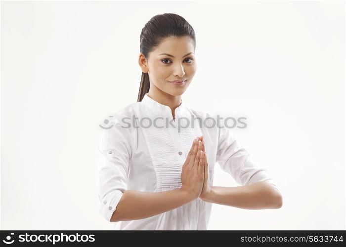 Portrait of smiling young woman with hands clasped over white background