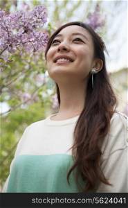 Portrait of smiling young woman with long hair outdoors in the park in springtime