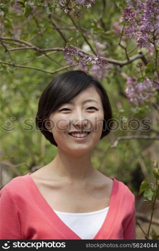 Portrait of smiling young woman with medium length hair outdoors in the park in springtime
