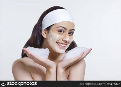 Portrait of smiling young woman with soap sud over white background
