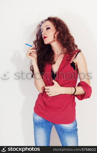 Portrait of smoking young brunette woman with long curly hair on a white background