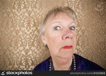 Portrait of snooty senior woman in front of gold background