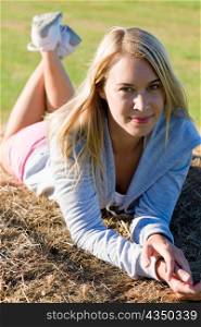 Portrait of sportive young woman relax on hay bales