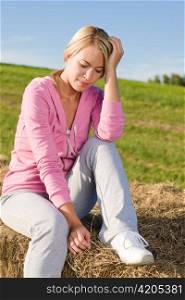 Portrait of sportive young woman relax sitting on hay bales