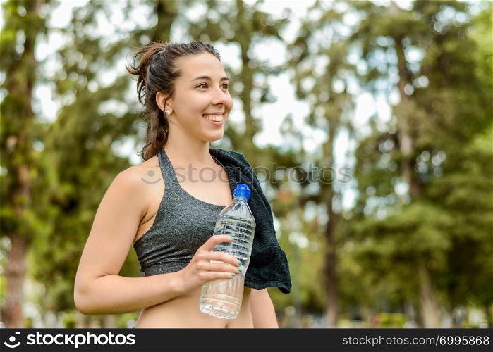 Portrait of sportswoman drinking water after workout. Outdoors